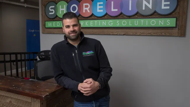 Man standing in front of Shoreline Media Marketing Solutions sign, showcasing the agency's branding and expertise in digital marketing and SEO services for New Jersey businesses.