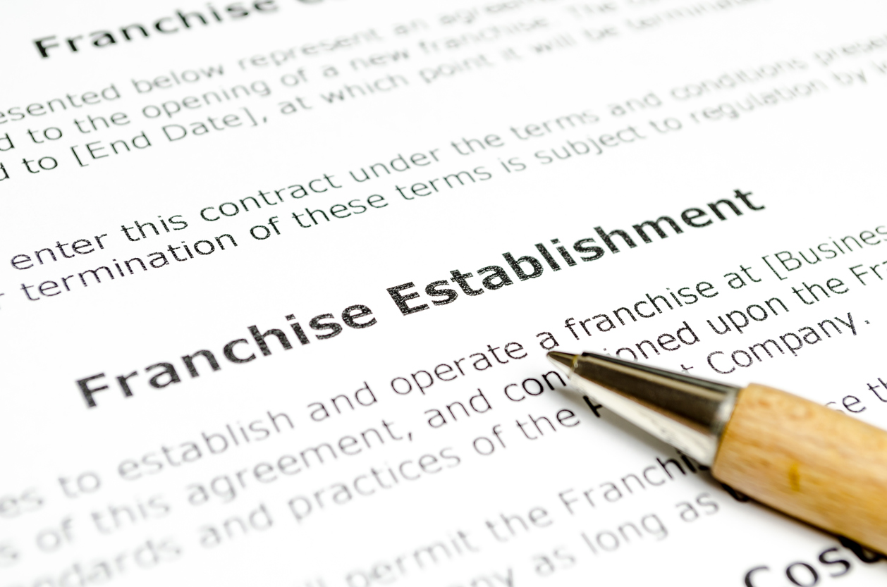 Franchise establishment contract document with highlighted text and a pen, emphasizing franchise marketing strategies and agreements.