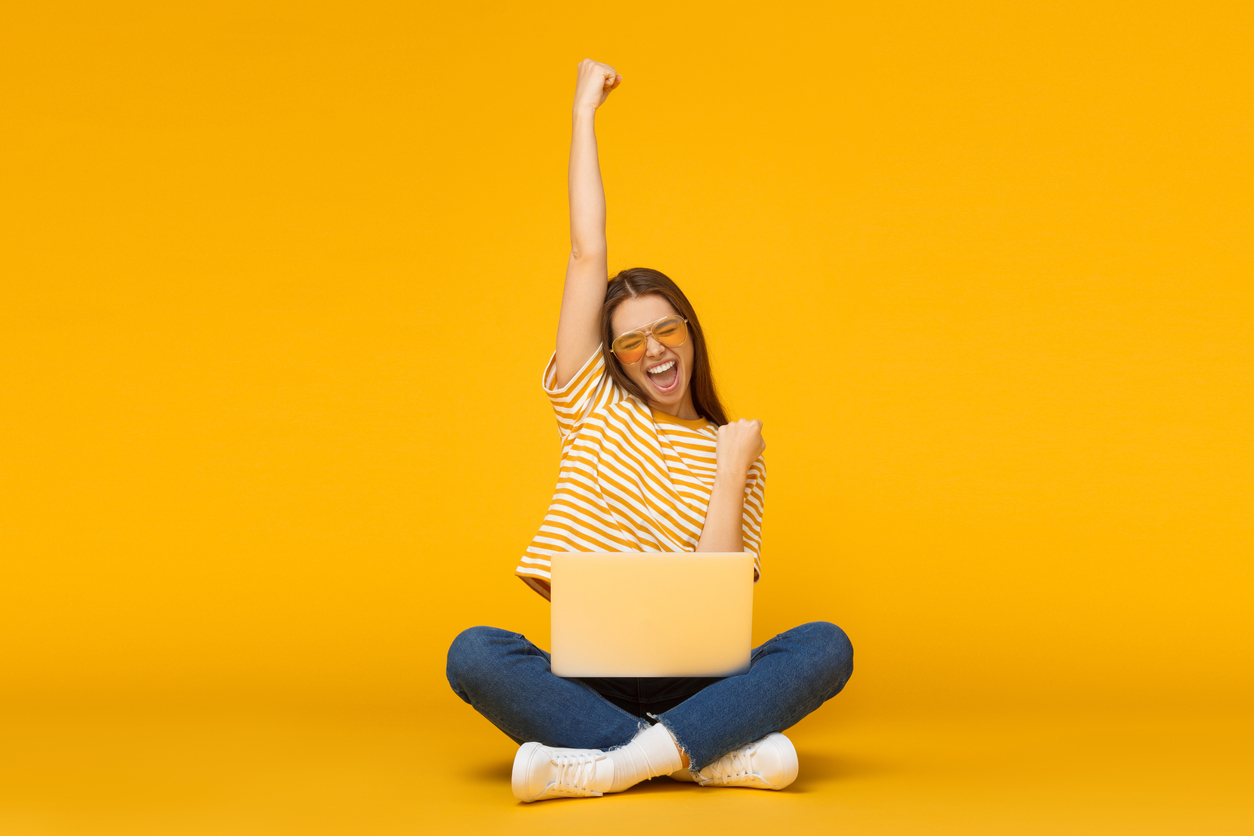 Cheerful woman celebrating success while working on a laptop, symbolizing effective digital marketing strategies like PPC and SEO.